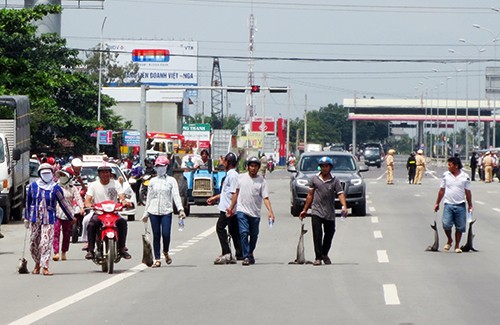 Dân bức xúc vì cá chết hàng loạt trên sông Chà Và Các hộ dân kéo lê cá chết trên quốc lộ 51. Ảnh: Vnexpress
