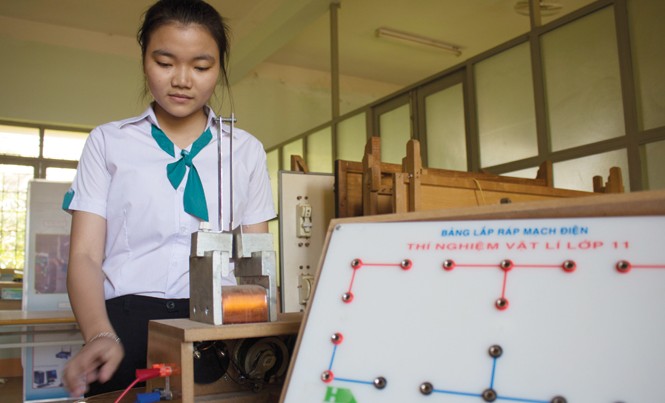 Nữ sinh trường huyện sáng chế phanh điện từ Nguyễn Việt Trinh bên mô hình phanh điện từ.