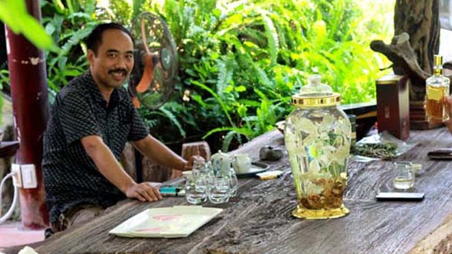 Chuyện người đàn ông dốc tiền 'chơi' Sâm Ngọc Linh Anh Tuyền ngồi ngắm bình rượu sâm trên chiếc bàn gỗ hóa thạch khổng lồ, giữa khu vườn đầy hoa lá, chim muông
