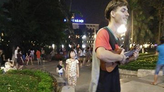 Chàng trai Tây hát xin tiền trên phố Hà Nội để đi du lịch Anh chàng tự tin đàn hát trên phố đi bộ. Ảnh: Nguyễn Trung.