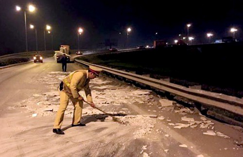 Cảnh sát cùng dân dọn đá rơi vãi trên quốc lộ trong đêm Tổ công tác cảnh sát giao thông, thay nhau đứng ra phân luồng và mượn chổi, xẻng quét dọn đá rơi vãi trong đêm.Ảnh: Nguyên Dân.
