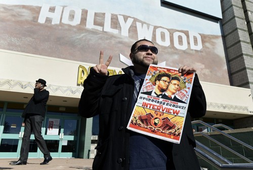 Phim ám sát Kim Jong-un thu về 36 triệu USD Một khán giả cầm poster phim The Interview trước rạp phim ở Los Angeles, California vào ngày công chiếu 25/12. Ảnh: Reuters.