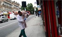 Một người đàn ông vác con lợn vào cửa hàng bán thịt ở London. (Ảnh: Reuters)
