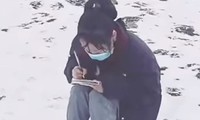 Cô nữ sinh ngồi học bài trên núi phủ đầy tuyết. (Ảnh từ clip)
