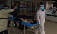 Các tình nguyện viên đưa một phụ nữ mang thai đến bệnh viện ở Vũ Hán để xét nghiệm Covid-19. (Ảnh: Xinhua)