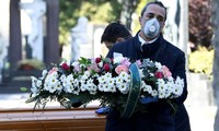 Một nhân viên tang lễ Italy đeo khẩu trang trong đám tang của bệnh nhân Covid-19. (Ảnh: Reuters)