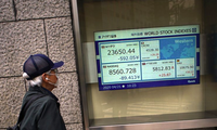 Một người đàn ông đeo khẩu trang nhìn bảng điện tử chỉ số chứng khoán thế giới bên ngoài một công ty chứng khoán ở Tokyo ngày 21/4. (Ảnh: AP)