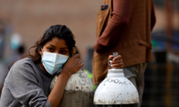 Một phụ nữ ở Kathmandu ôm bình oxy cho bệnh nhân COVID-19. (Ảnh: Reuters)