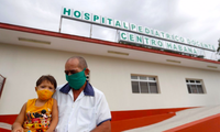 Một ông bố bế con trai bên ngoài bệnh viện ở Hanava, nơi đang triển khai tiêm vắc-xin COVID-19 cho nhóm trẻ từ 2 tuổi. (Ảnh: EPA)