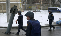 Lực lượng Ukraine đứng gần một rocket bị mắc kẹt ở Kharkiv ngày 25/2. (Ảnh: Reuters)