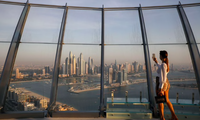 Một phụ nữ đang chụp ảnh bằng điện thoại từ toà tháp ở Dubai. (Ảnh: Reuters)