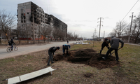 Người dân Mariupol đào huyệt tạm ven đường để chôn hàng xóm ngày 20/3. (Ảnh: Reuters)
