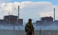 Một lính mặc đồng phục mang cờ Nga đứng canh trước nhà máy điện hạt nhân Zaporizhzhia. (Ảnh: Reuters)