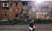 Một phụ nữ đi qua toà nhà bị trúng tên lửa ở Bakhmut, Ukraine. (Ảnh: Reuters)