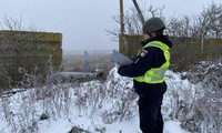 Một cảnh sát Ukraine đứng gần tên lửa hành trình Nga bị bắn hạ ở Kiev ngày 16/12 