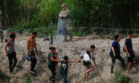 Người di cư đi dọc theo sông Rio Bravo để trình diện cơ quan hải quan và bảo vệ biên giới Mỹ. (Ảnh: Reuters)