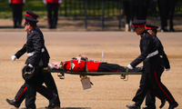 Một người chơi kèn của đội quân nhạc được đưa đi bằng cáng sau khi ngất xỉu trong lễ diễu hành. (Ảnh: AP)