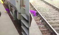 Hình ảnh người phụ nữ che chở cho 2 con dưới đường ray trong video 