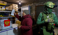 Một người dân đi bỏ phiếu vào thùng ngay cạnh lính gác ở thành phố Avdiivka, vùng Donetsk, ngày 16/3. (Ảnh: Reuters)