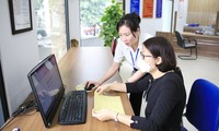 Cán bộ công chức hỗ trợ người dân thực hiện giao dịch trên Cổng dịch vụ công trực tuyến tại bộ phận “một cửa” quận Tây Hồ (Ảnh: Quang Thái)