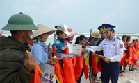 Vùng CSB 1 tặng cờ Tổ quốc và cấp phát tờ rơi tuyên truyền cho bà con ngư dân ở huyện Lệ Thủy (Quảng Bình). Ảnh: M.T