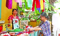 Chị Trương Nguyễn Hoài An, người sáng lập Chợ phiên thủ công (bên phải) hỗ trợ các cư dân của xóm bày biện, sắp xếp hàng hóa Ảnh: Giang Thanh 