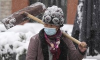 Mùa đông năm nay đến sớm ở nhiều tỉnh, thành phố Trung Quốc, khiến biến thể Delta dễ lây lan hơn. Trong ảnh, một phụ nữ vác xẻng đi giữa trời tuyết ở thủ đô Bắc Kinh ngày 7/11Ảnh: AP 