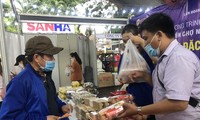 Trong bộ đồ công nhân, anh Nguyễn Hoàng Ngải (bên trái) vui mừng vì được tặng phiếu mua sắm tại phiên chợ nghĩa tình hôm 29/4 