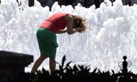 Một người phụ nữ lấy nước ở đài phun nước để hạ nhiệt