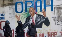 Cảnh sát đứng cạnh bức tranh tường phác họa chân dung Tổng thống Haiti Jovenel Moise gần dinh thự nơi ông bị ám sát ngày 7/7 Ảnh: AP 