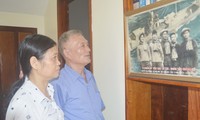 Bên bức ảnh tàu C235 treo tại nhà, CCB Lê Duy Mai kể cho chị Doãn Thị Thu về trận chiến đấu dũng cảm năm xưa của các đồng đội. Ảnh: Kiến Nghĩa