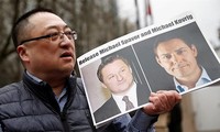 Một người biểu tình ở Vancouver, Canada cầm bức ảnh in hình ông Michael Spavor và ông Michael Kovrig (phải) kêu gọi Trung Quốc thả họ. Ảnh: REUTERS