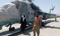 Hai tay súng Taliban đang đứng trước chiếc trực thăng vũ trang Mi-35.