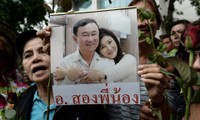 Một người ủng hộ gia đình Shinawatra giơ cao bức ảnh chụp chung của hai anh em cựu Thủ tướng Thái Lan Thaksin và Yingluck Shinawatra. Ảnh: AFP