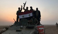 Quân đội Syria cầm quốc kì ăn mừng sau khi tiến vào thị trấn Albu Kamal hồi đầu tháng 11. Ảnh: AFP