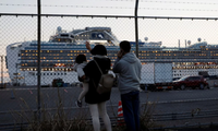 Thân nhân các hành khách mắc kẹt trên thuyền gọi điện và vẫy chào người nhà từ xa. Ảnh: Reuters