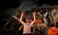 Người dân Dải Gaza đứng trước một tòa nhà bị sập ăn mừng thỏa thuận ngừng bắn. Ảnh: Reuters