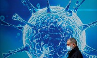 Một người đàn ông đeo khẩu trang đi qua tấm áp phích in hình virus corona ở Oldham, Anh. Ảnh: Reuters