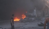 Người dân Syria đứng cạnh lửa, đống đổ nát và một xe tải hư hỏng sau một vụ không kích chết người ở tỉnh Idlib hôm 28/8.