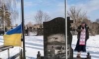 Linh mục Kostyantyn Kholodov, một tuyên úy quân đội, cầu nguyện ngày 6/22 ở Bucha, Ukraine, bên ngôi mộ của hai người đàn ông địa phương thiệt mạng trong cuộc xung đột với lực lượng ly khai ở miền đông nước này. Ảnh: The Washington Post. 
