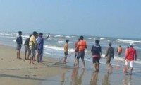 Lực lượng cứu hộ và người dân tổ chức tìm kiếm nạn nhân tại khu vực bãi biển Quất Lâm - Ảnh: Hoàng Long