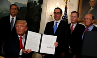 Tổng thống Mỹ Donald Trump ký văn bản ủy quyền cho Đại diện Thương mại Mỹ Robert Lighthizer để xem xét mở cuộc điều tra thương mại đối với Trung Quốc hôm 14/8. Ảnh: Reuters
