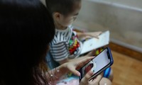 Làm việc trong nhà mùa dịch, nhiều phụ huynh dùng điện thoại làm “vú em” cho con. Ảnh: Như Ý