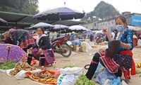 Khi chợ vắng khách, phụ nữ Mông tranh thủ thêu váy áo Ảnh: LỘC LIÊN