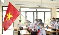 Học sinh đeo khẩu trang, chào cờ tại lớp học trong ngày đầu trở lại trường 