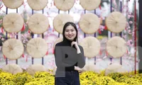 Các bạn trẻ chụp ảnh lưu niệm tại mô hình nón quai thao ở đường hoa Tết. Ảnh: Nguyễn Thắng.