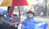 Tình nguyện viên đội mưa che ô cho thí sinh và phụ huynh