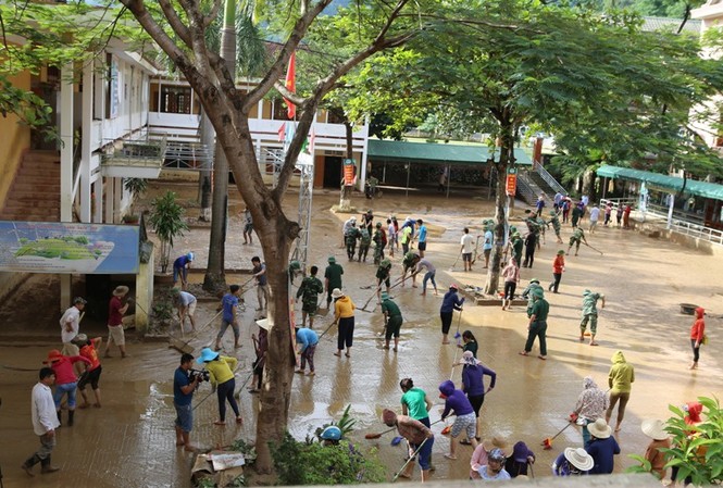 Trường học ngổn ngang bùn đất, ngày tựu trường bị hoãn Hàng chục người nỗ lực dọn bùn đất sau mưa lũ.