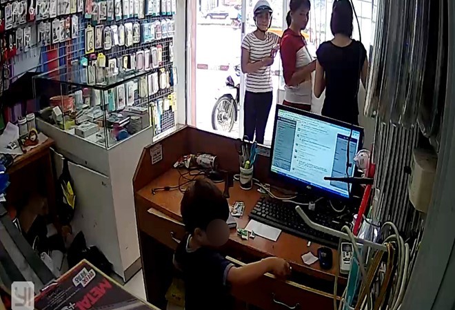 Bé trai trộm điện thoại theo ám hiệu của chị Bé trai lấy cắp điện thoại di động trong cửa hàng. Ảnh: Cắt từ clip
