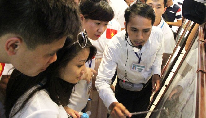 Loan báo chính nghĩa đến bạn bè năm châu Thanh niên kiều bào chăm chú nghe thuyết minh về các bản đồ, tư liệu chủ quyền của Việt Nam đối với Hoàng Sa, Trường Sa. Anh: H.Văn